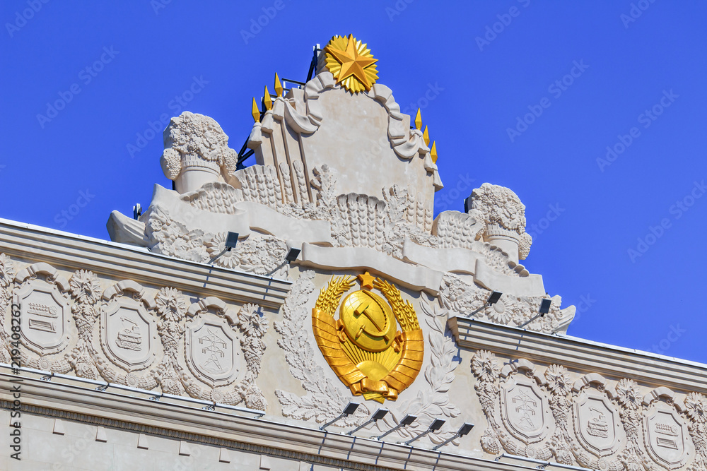 Obraz premium Gilded coat of arms of Soviet Union closeup on facade of pavilion Space on VDNH in Moscow on a sunny summer morning