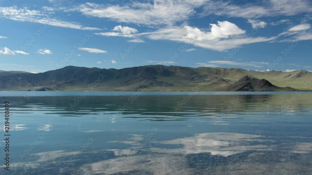 Waters of mongolian lake Tolbo-Nuur surrounded by mountains in north Mongolia under sky and clouds Waters of mongolian lake Tolbo-Nuur surrounded by mountains in north Mongolia under sky and clouds