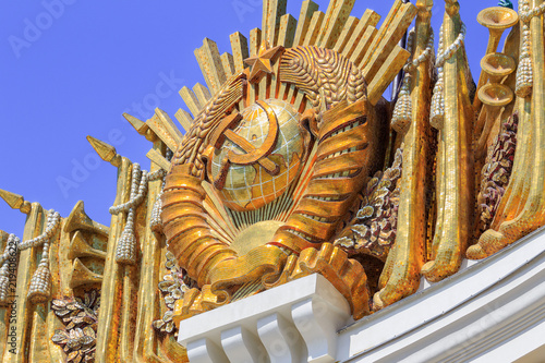 Gilded coat of arms of Union of Soviet Socialist Republics closeup on a blue sky background on the facade of pavilion Central on VDNH in Moscow photo