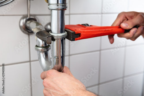 Plumber Repairing Sink With Adjustable Wrench