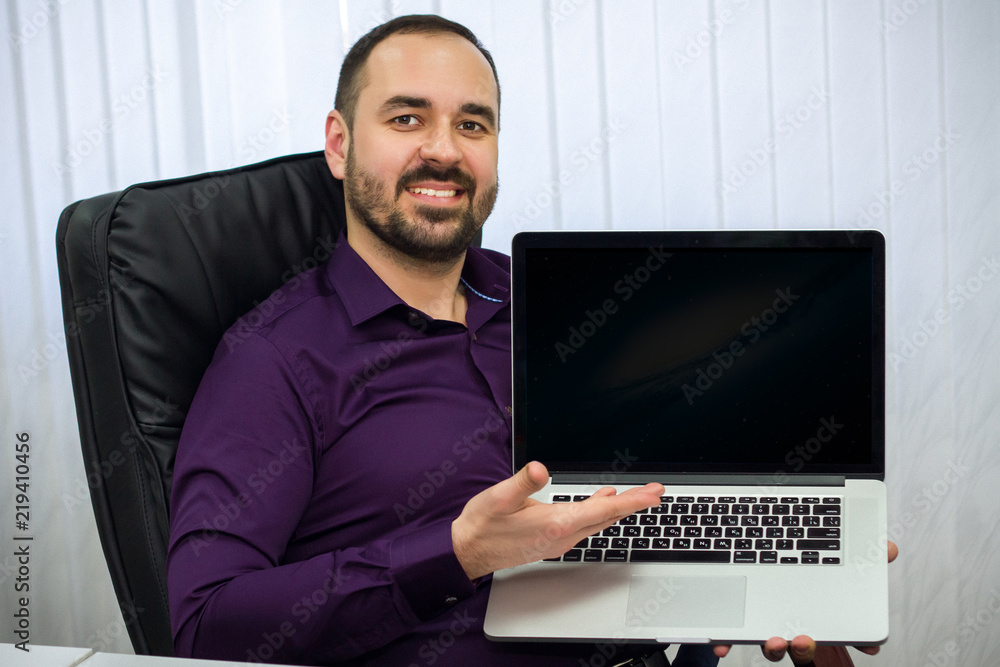 man sitting in armchair, smiling and showing his hand on laptop man sitting in armchair, smiling and showing his hand on laptop