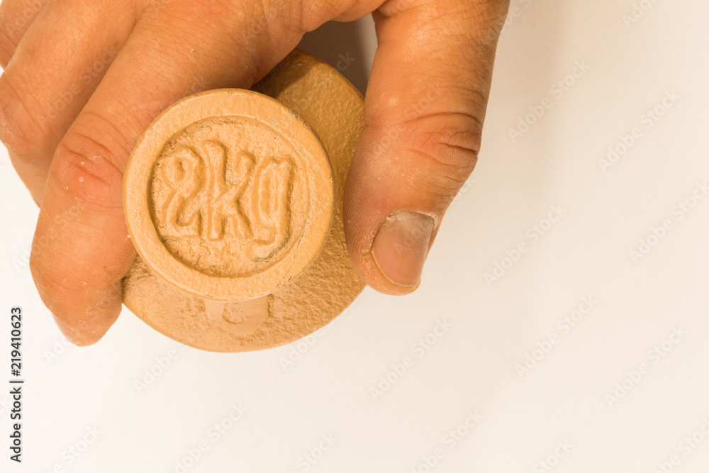 Fototapeta premium Hand holds 2kg weight balance measurement on white background