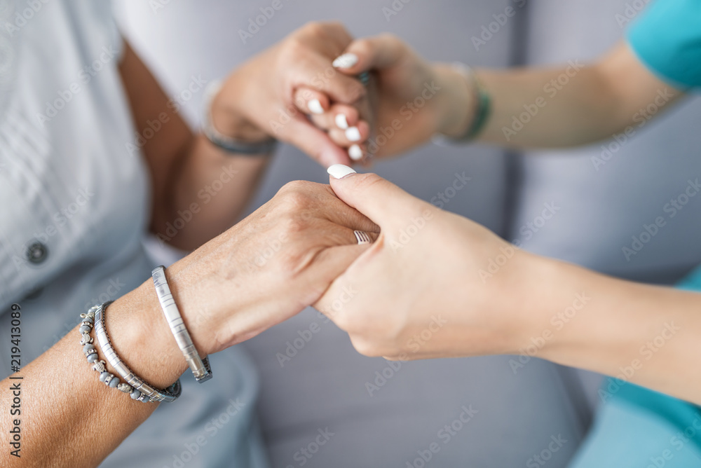 Close-up of young person's hand holding elderly person's hand as sign of caring for seniors Close-up of young person's hand holding elderly person's hand as sign of caring for seniors