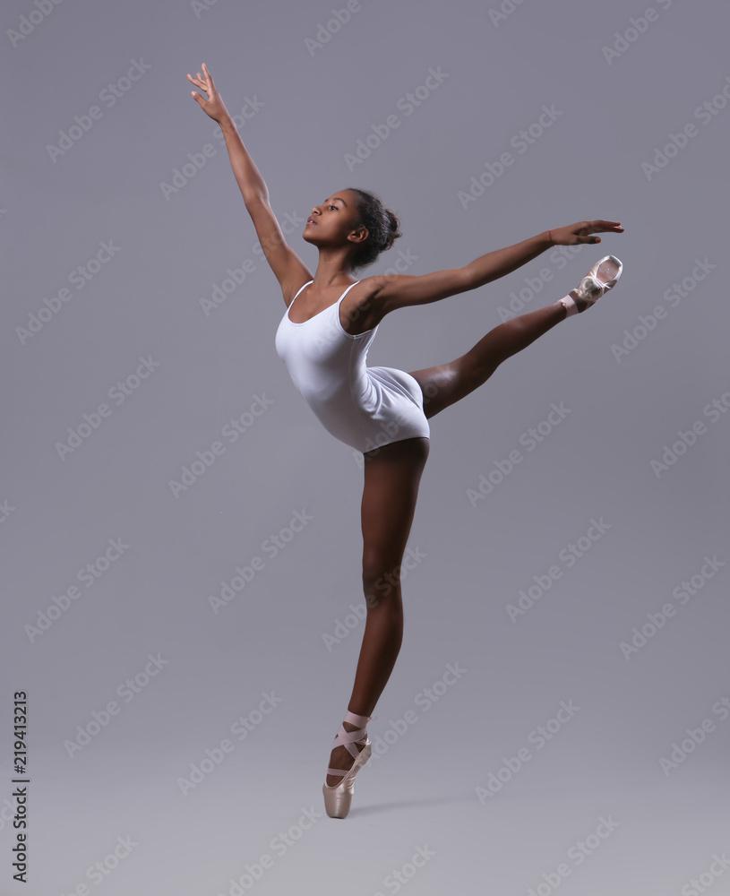 A ballerina in a white leotard makes a pose 