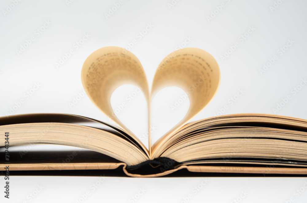 close up of opened book with heart shaped from two pages, isolated on white background. close up of opened book with heart shaped from two pages, isolated on white background.