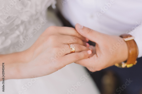 Closeup view of young white just married couple holding hands after ceremony on wedding day. Horizontal color photography.