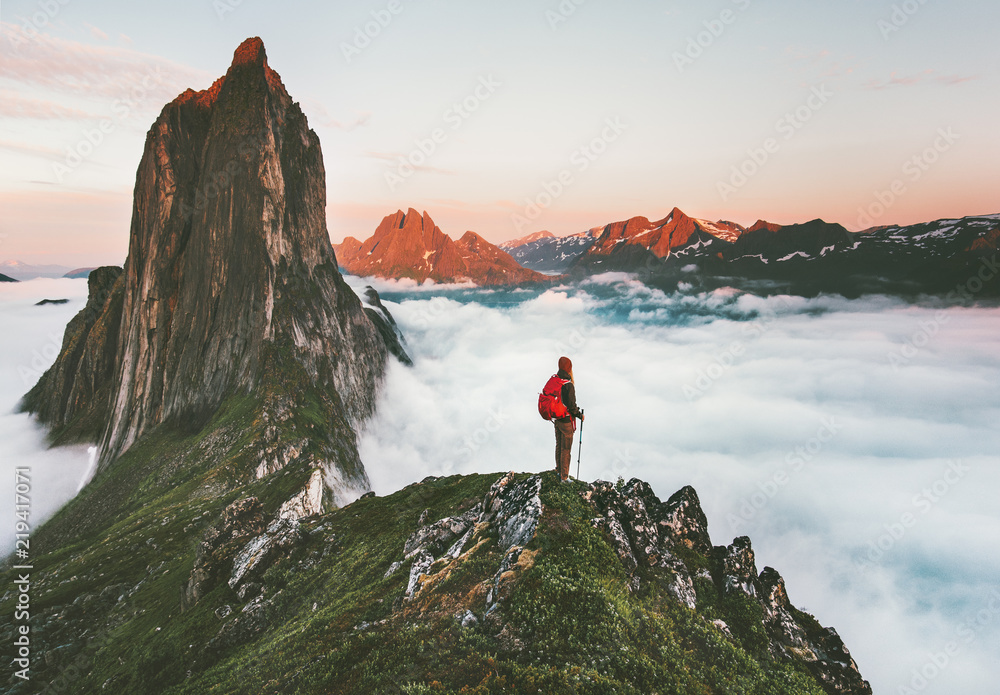 Traveler on cliff over clouds exploring sunset Segla mountain alone hiking adventure journey outdoor Norway vacations traveling lifestyle weekend getaway