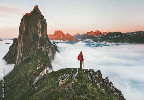 Traveler on cliff over clouds exploring sunset Segla mountain alone hiking adventure journey outdoor Norway vacations traveling lifestyle weekend getaway photo