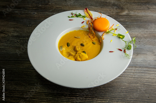 fresh pumpkin cream soup with orange macaroon decoration