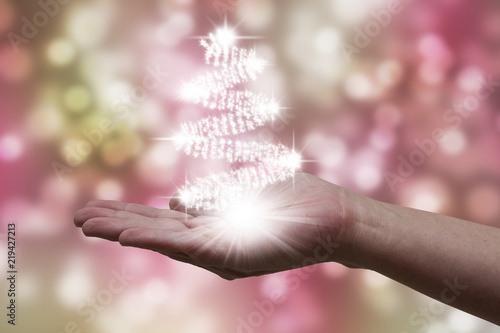 Bright christmas lights in female hand, creating a christmas tree on colored background © Carlos
