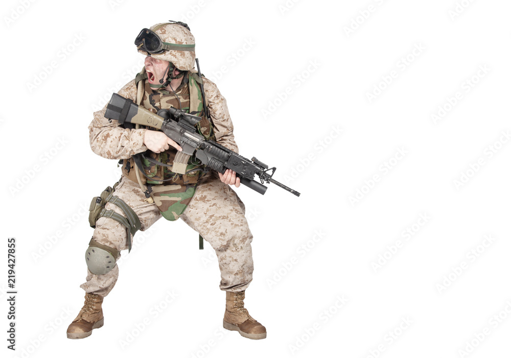 Studio shoot of modern infantry soldier, U.S. marine rifleman in combat uniform, helmet and body armor, screaming and crouching down with assault service rifle in hands isolated on white background Studio shoot of modern infantry soldier, U.S. marine rifleman in combat uniform, helmet and body armor, screaming and crouching down with assault service rifle in hands isolated on white background