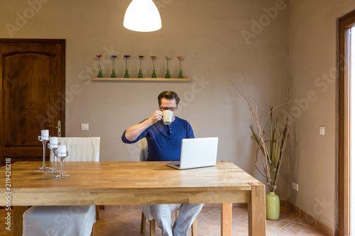 Mann trinkt Kaffee während er am Notebook arbeitet photo