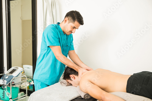 Man Getting Neck Massage From Therapist At Clinic
