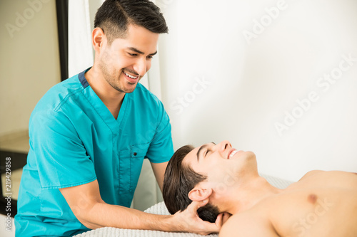 Physiotherapist Pressing Head Of Athlete In Clinic