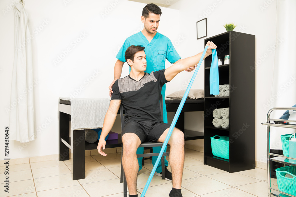 © AntonioDiaz - Physiotherapist Assisting Athlete In Performing Stretching Exercise With Resistance Band © AntonioDiaz - Physiotherapist Assisting Athlete In Performing Stretching Exercise With Resistance Band