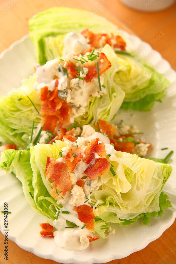 Vertical view of lettuce wedges topped with blue cheese dressing, bacon and chives Vertical view of lettuce wedges topped with blue cheese dressing, bacon and chives
