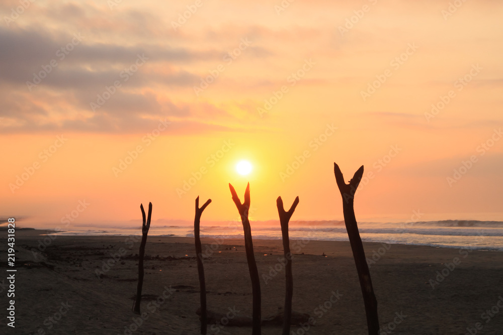 Tropical Sunrise over Fishing Net Drying Posts on Pacific Ocean Beach.