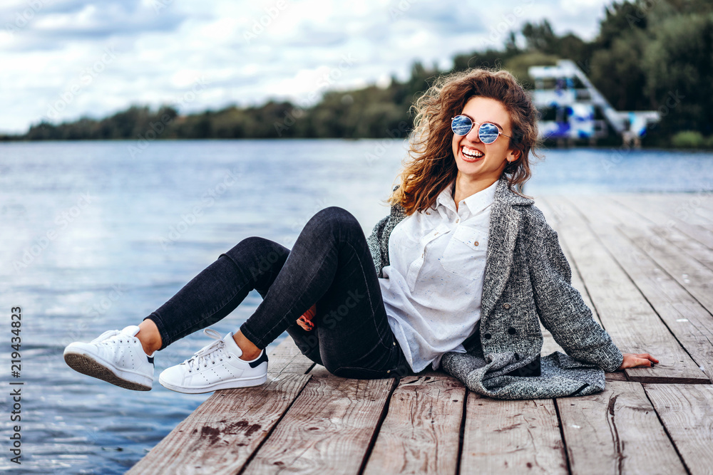 Cute girl with curly hair relaxing near lake