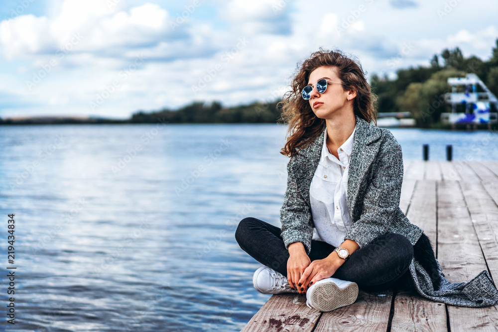 Cute girl with curly hair relaxing near lake Cute girl with curly hair relaxing near lake