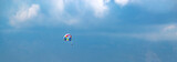 Человек с парашютом в голубом небе в облаках, над горами