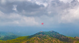Человек с парашютом в голубом небе в облаках, над горами