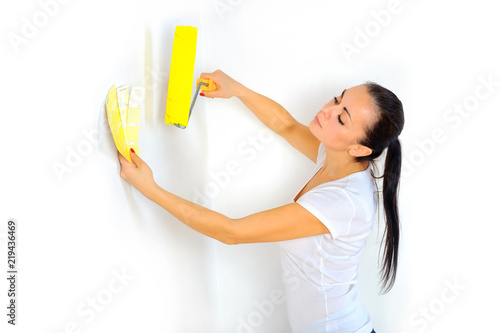 woman painter with a roller in his hand picks up the color on the tile palette for painting the wall