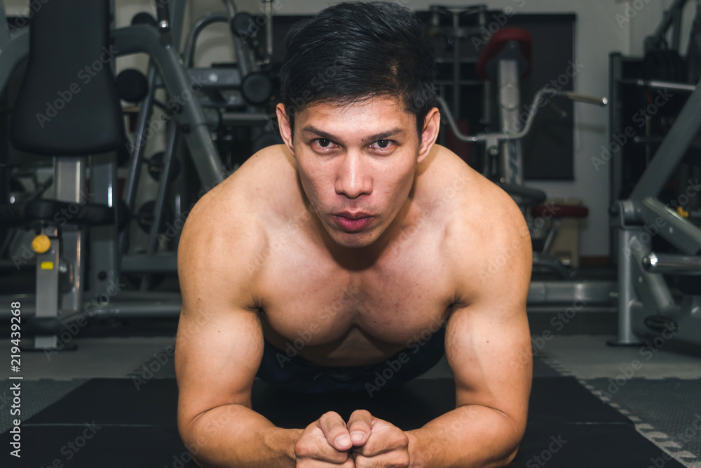 Asian muscular men are lifting weights in the gym.