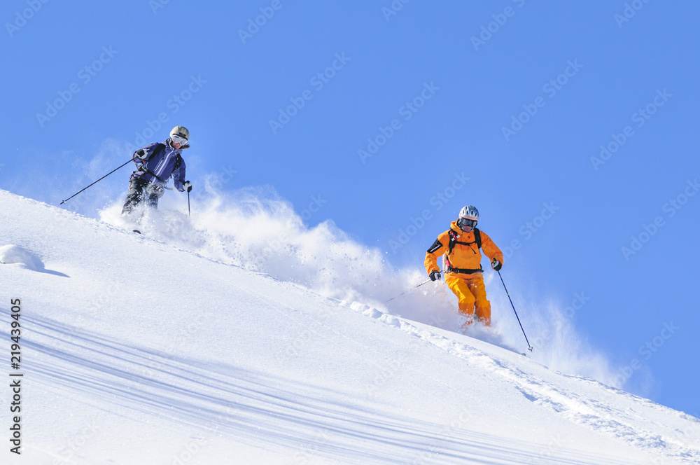 zwei Skifahrer genießen den traumhaften Tiefschnee-Hang