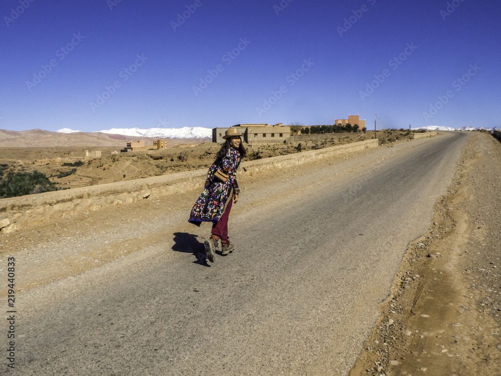 Female traveler running into the deserted road in Morocco