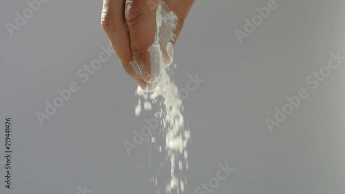 Baker's hands throwing the flour on a gray background in slow motion