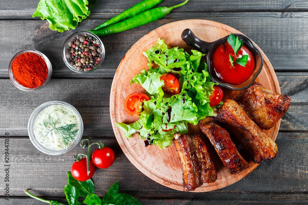 Grilled Beef steak with fresh vegetable salad, tomatoes and sauce on wooden cutting board Grilled Beef steak with fresh vegetable salad, tomatoes and sauce on wooden cutting board