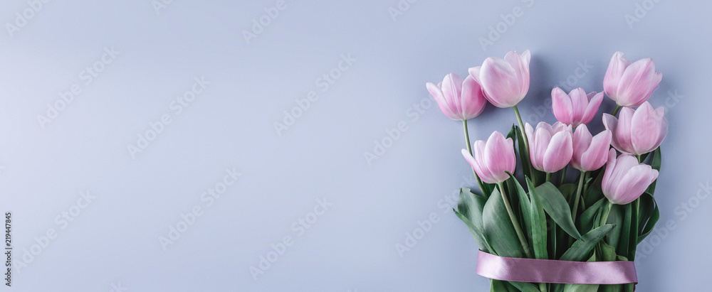 Bouquet of pink tulips flowers on blue background. Waiting for spring. Flat lay, top view