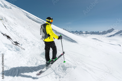 Portrait of a professional freerider skier standing on a snowy slope against the background of snow-capped mountains. The concept of winter sports