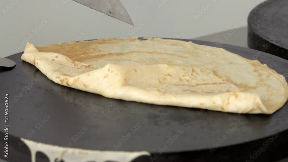 Cook folds the finished pancake and removes it from the plate in slow motion Cook folds the finished pancake and removes it from the plate in slow motion