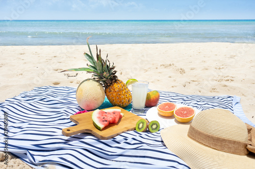 Beach picnic with lemonade and fruits (pineapple, grapefruit, kiwi, watermlon, cantaloupe, mango) photo