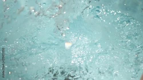Slow motion close up, pineapple falls into pool
