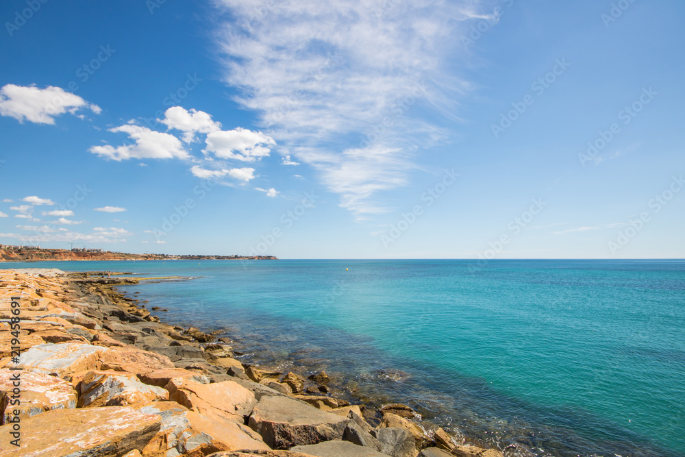 Rocks of the marina and clear blue water at the Mediterranean Sea on a summer day