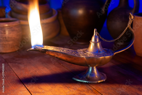 Ancient oil lamp burns on a wooden table