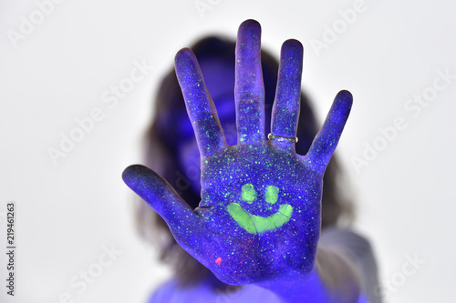 Self portrait with ultraviolet lights and neon paint make up to make the design glow in the dark. Stop and smile concept.