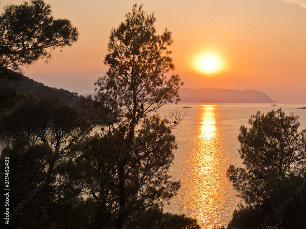 Sunset behind Skiathos island, a view from the road above Kastani beach, island of Skopelos, Greece Sunset behind Skiathos island, a view from the road above Kastani beach, island of Skopelos, Greece