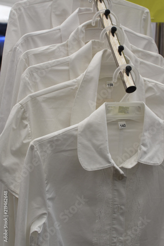 back to school. a lot of white shirts on a hanger. school uniform for children.