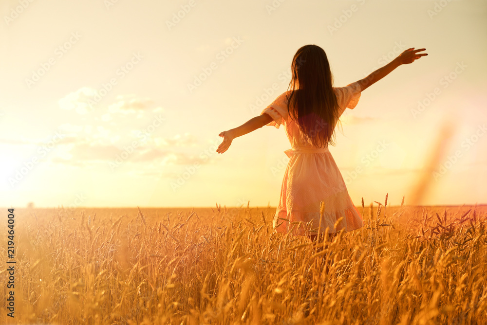 Woman in wheat field at sunset