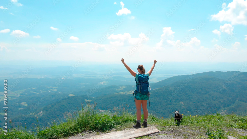 AERIAL: Flying around a girl standing atop of a mountain with outstretched arms. AERIAL: Flying around a girl standing atop of a mountain with outstretched arms.