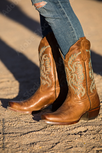 Female in brown cowboy boots on gravel road