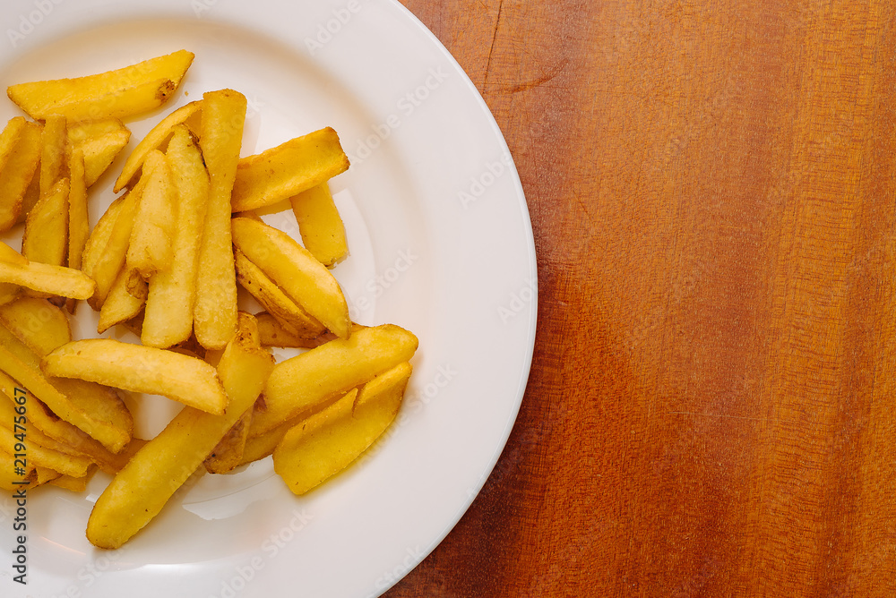French potatoes fries in the white plate on wooden background. French potatoes fries in the white plate on wooden background.