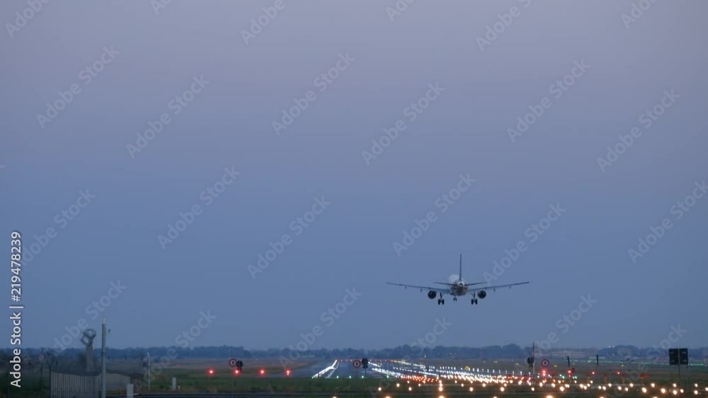 Airplane approaching the landing strip at dusk, seen from back Airplane approaching the landing strip at dusk, seen from back