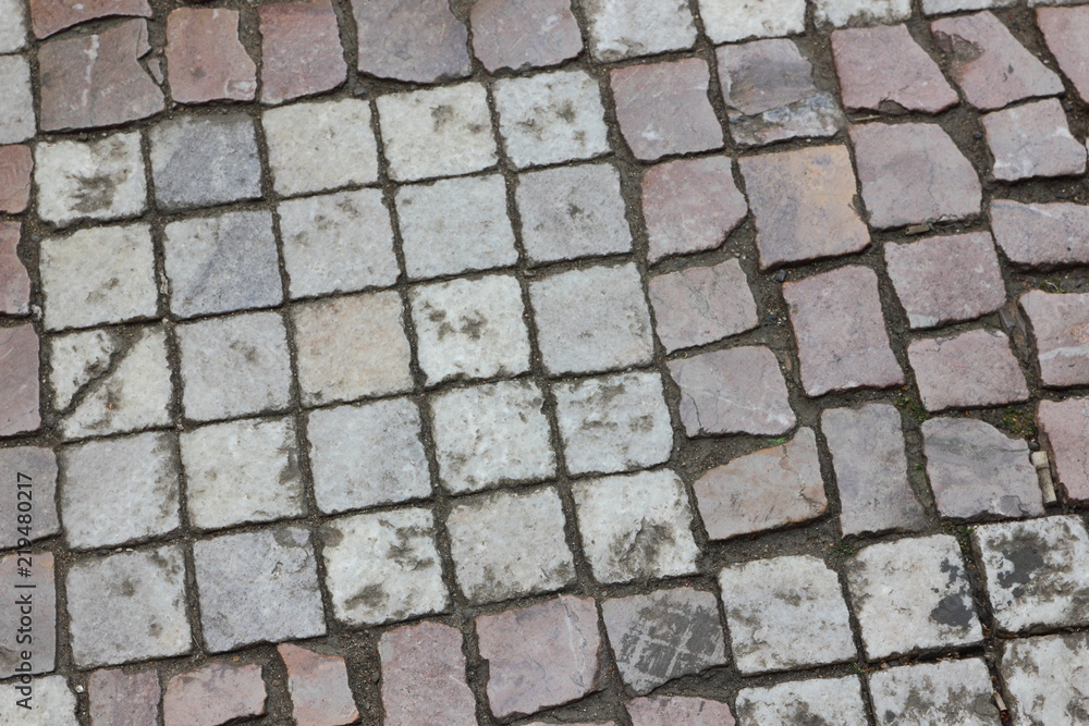 Cobbles close-up. An ancient road lined with a stone in Prague. Texture of smooth stones. Background old stone road in the city. Pattern with natural material