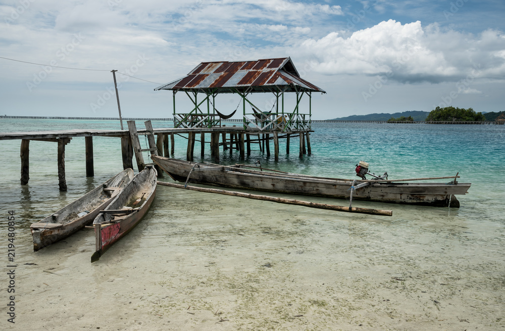 Tropical sand beach resort on remote Malenge island, part of Togean archipelago with traditional boats, Indonesia