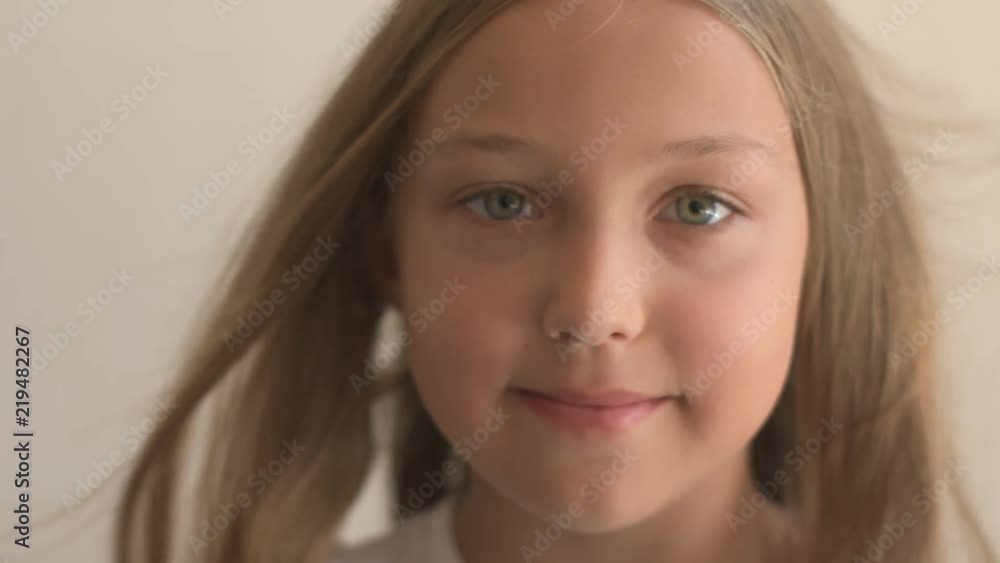 Close Up Portrait of happy young girl with blue eyes and blond hair. Standing on Wind. Breeze is playing with girl's hair. Stormy weather, autumn, winter, spring. Old style vintage. Shallow focus Close Up Portrait of happy young girl with blue eyes and blond hair. Standing on Wind. Breeze is playing with girl's hair. Stormy weather, autumn, winter, spring. Old style vintage. Shallow focus