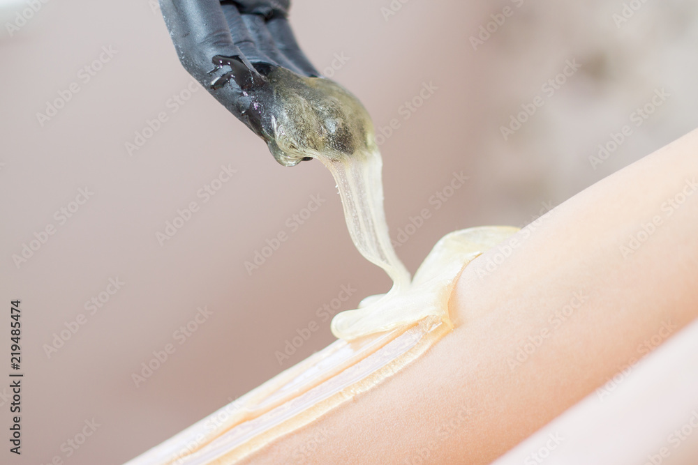 procedure of hair removing on leg beautiful woman with sugar paste or wax honey and black gloves hand - depilation and beauty concept